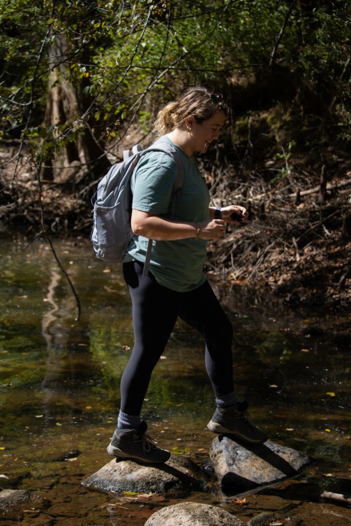 girl crossing river by stepping on rocks
