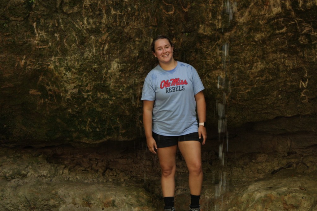 girl standing behind waterfall at clark creek natural area